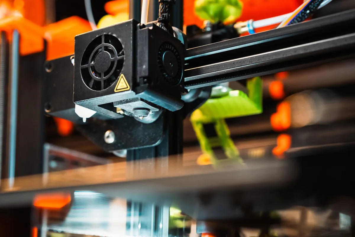 Close-up of a 3D printer extruder, cooling fan, and hotend assembly, the area to check when a 3D printer is not extruding filament