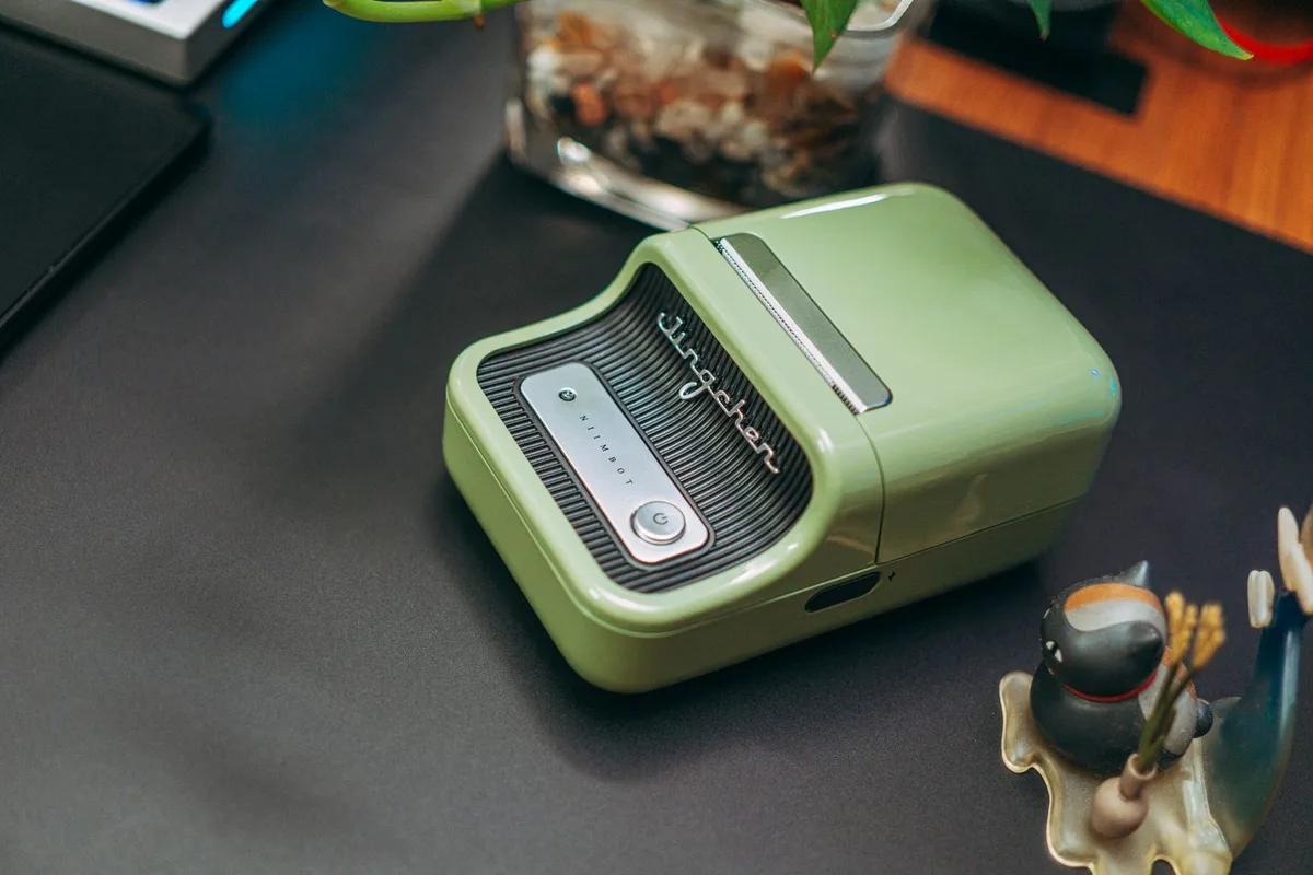 Compact green NIIMBOT portable Bluetooth label printer sitting on a desk